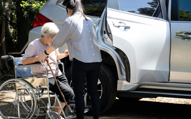 Asian female caregiver helping disabled elderly woman in wheelch